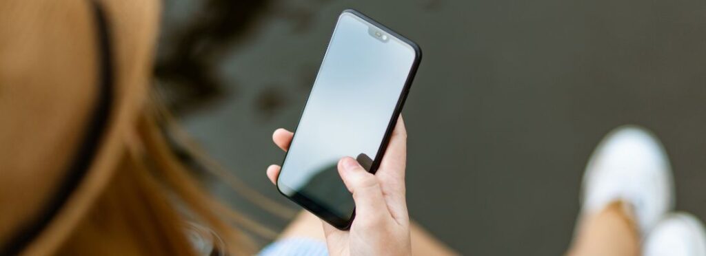 Una donna tiene in mano uno smartphone spento